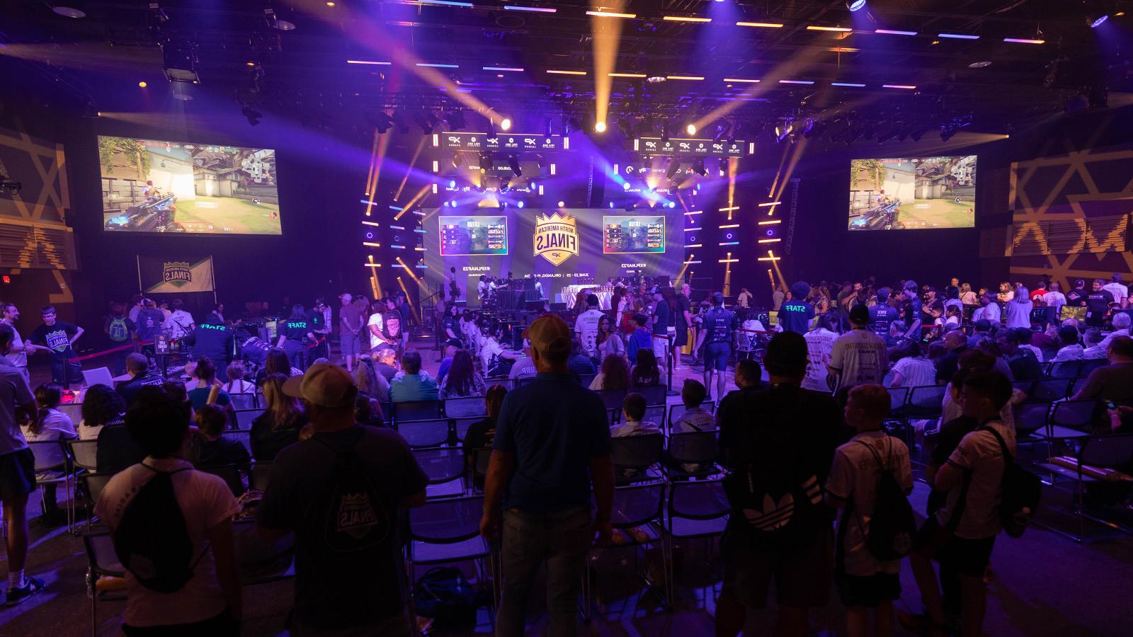 观看电子竞技比赛的一大群人, 房间前面的一个大LED屏幕上写着“北美总决赛”.’